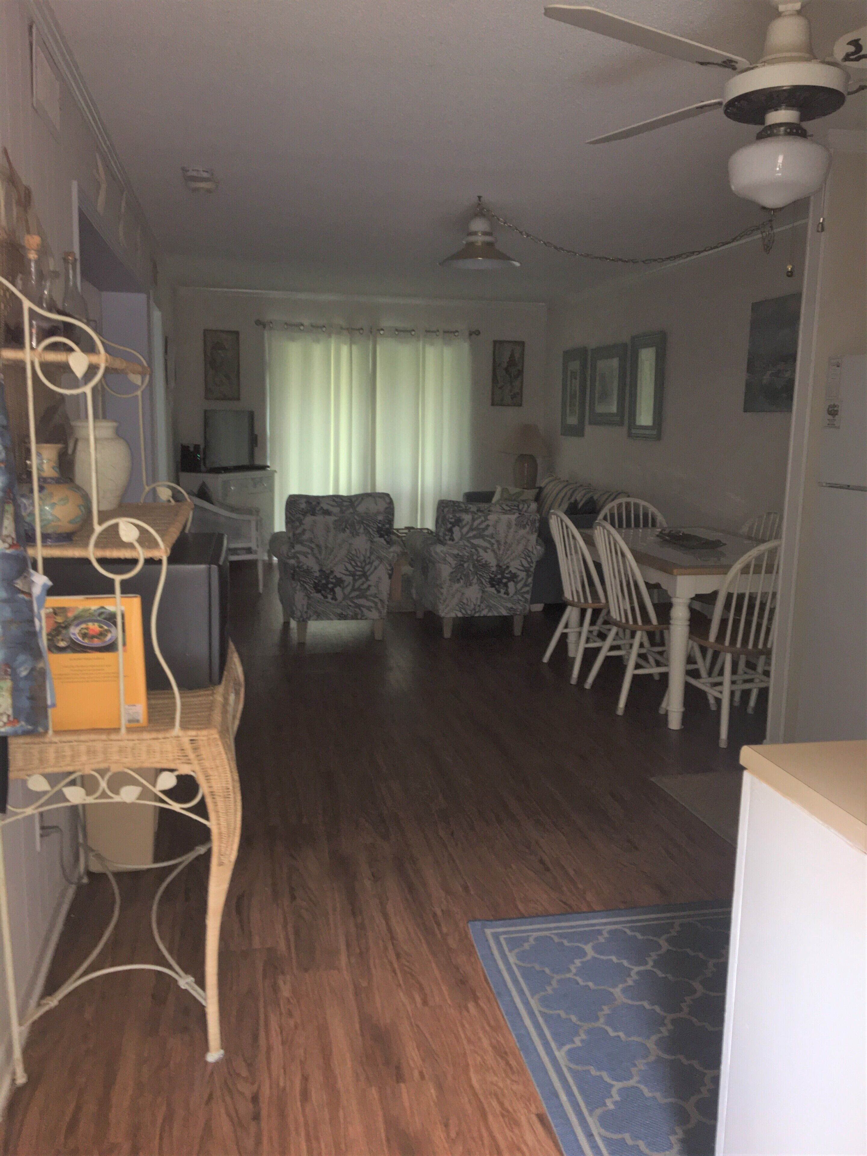 A living room with a dining area, wooden flooring, and a ceiling fan.