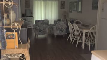 A living room with a dining area, wooden flooring, and a ceiling fan.