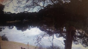 Blick auf einen See mit einem Baum im Vordergrund und einem Boot am linken Ufer.
