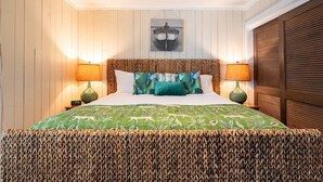 Un lit bien fait, recouvert d’une couvre-lit à motifs verts, avec deux oreillers et deux lampes de chevet.