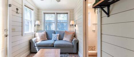 A cozy room with a grey sofa, a wooden coffee table, and a ceiling fan.
