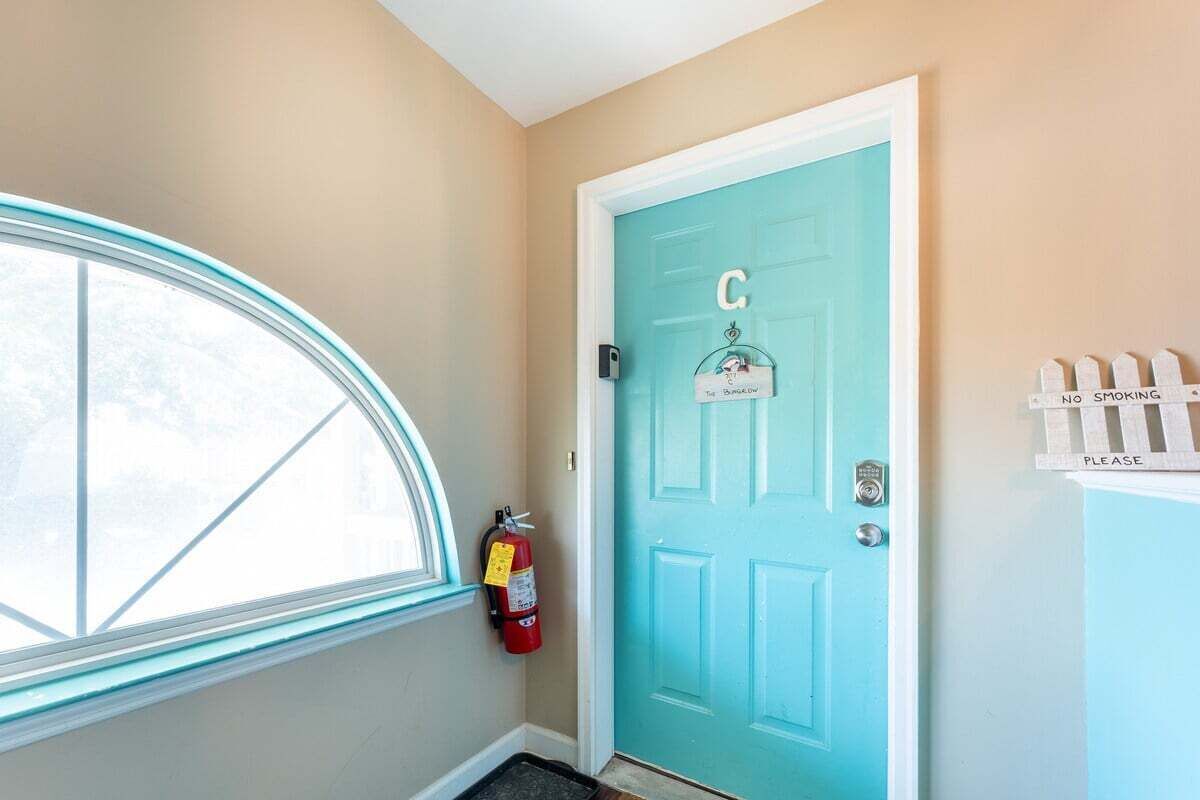A teal door with a 'C' sign, a fire extinguisher, and a 'NO SMOKING' sign.
