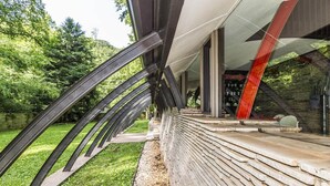En modern arkitektonisk konstruktion med böjda metallbalkar och en bas av sten.
