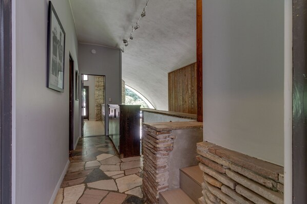 A hallway with a stone floor, a wooden bench, and a stone wall.