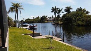 Uma correnteza tranquila com barcos atracados, cercada por vegetação exuberante e palmeiras.