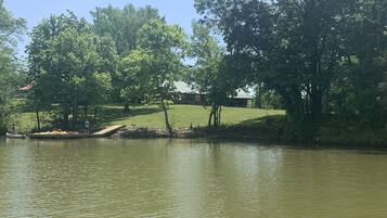 A calm lake with trees and a grassy area.