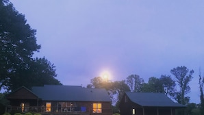 A two-story log cabin with a porch and a covered outdoor area. - Beautiful, Cedar Lakeside Cabin with Private Dock (Cadiz)