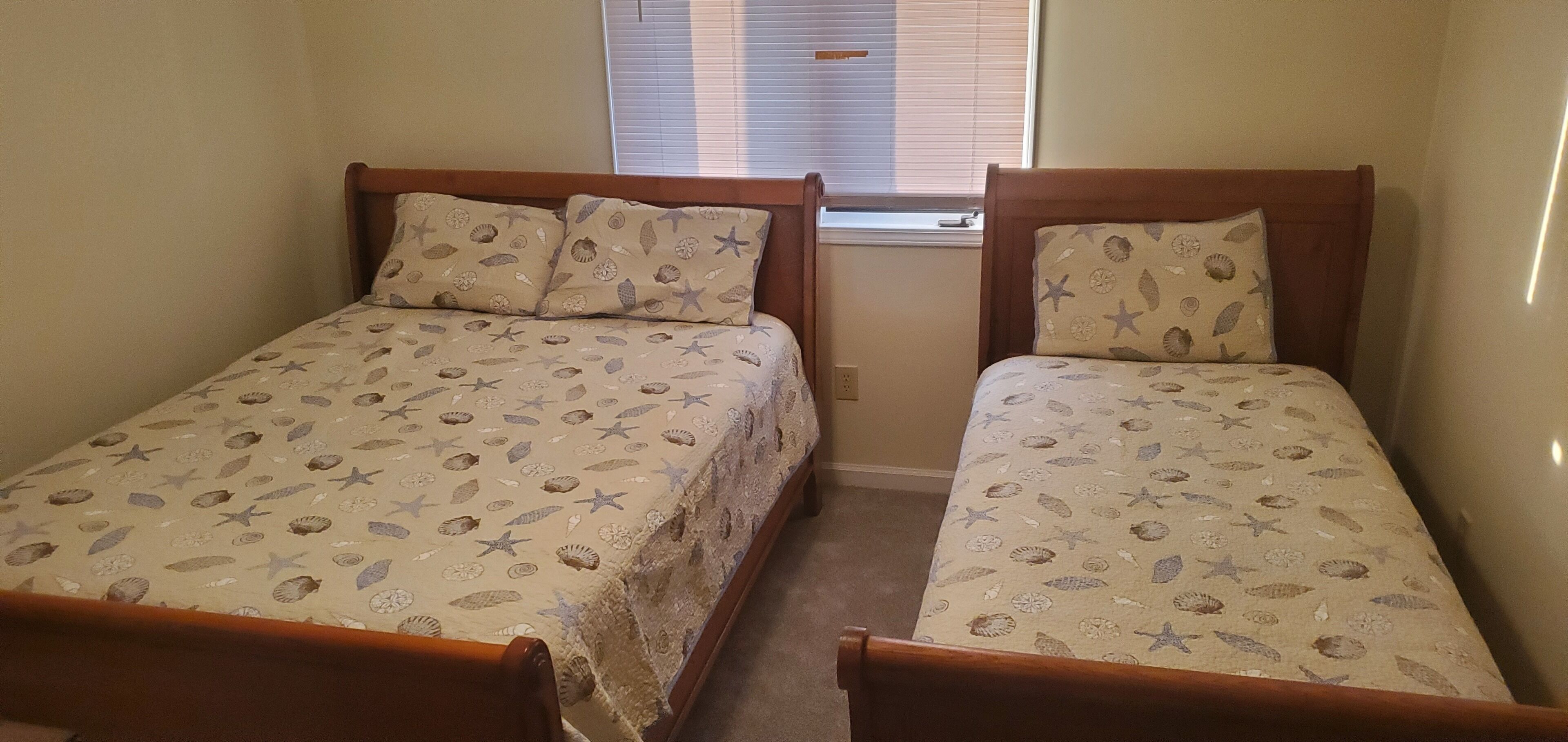A room with two single beds, each with a wooden headboard and a patterned bedspread.