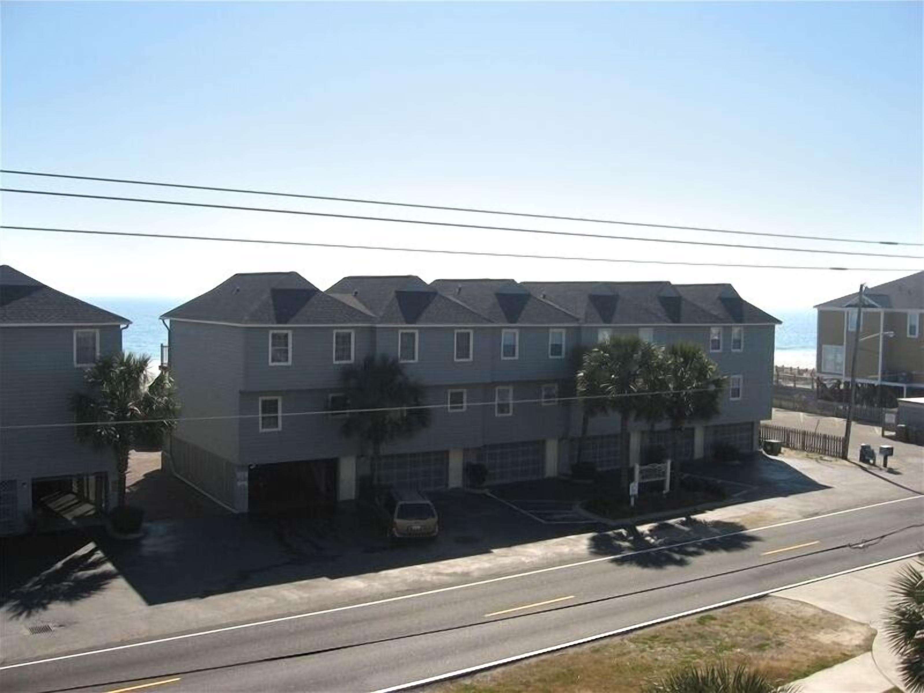 A multi-story residential building with a garage, a driveway, and a street view.