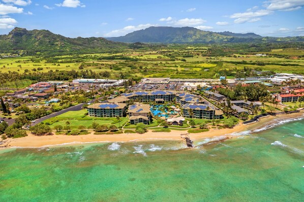 A resort with multiple buildings, a beach, and clear turquoise waters.