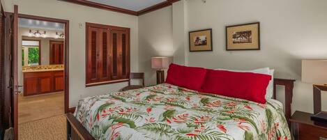 Een hotelkamer met een bed, nachtkastje, lamp, spiegel en een deur naar een badkamer.