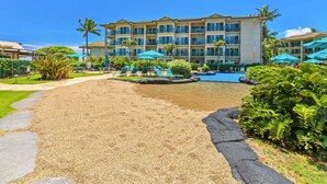 A resort with a pool, lounge chairs, and a building with multiple balconies. - Waipouli Beach Resort - Ground Floor #E103,  2 King Masters Suites (Kapaa)