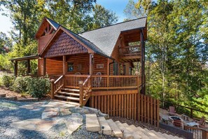 A wooden cabin with a stone staircase leading to a deck, surrounded by trees. - Honeybear Lodge by Mountain Oasis | Luxury Blue Ridge Cabin Rental Near Downtown (Blue Ridge)