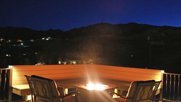 Eine Terrasse mit Feuerstelle, zwei Stühlen und einem Tisch.