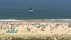 A beach with numerous colorful umbrellas and people enjoying the sand and water. - Carousel Oceanfront Condo w/ Stunning Ocean & Bay Views! (Ocean City)