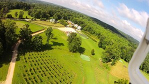 Vue aérienne d’une propriété rurale comprenant un grand champ, un labyrinthe délimité par des clôtures et un petit bâtiment surmonté d’un toit végétalisé.