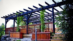 Une pergola en bois ornée de plantes grimpantes, une terrasse en bois et des marches en pierre.