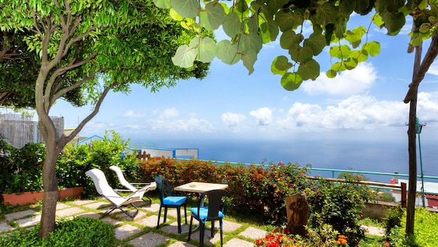 A patio with a table and chairs, surrounded by a garden with various plants and flowers. - IL RIFUGIO DI ELA 'Apartment Garden. (Furore)