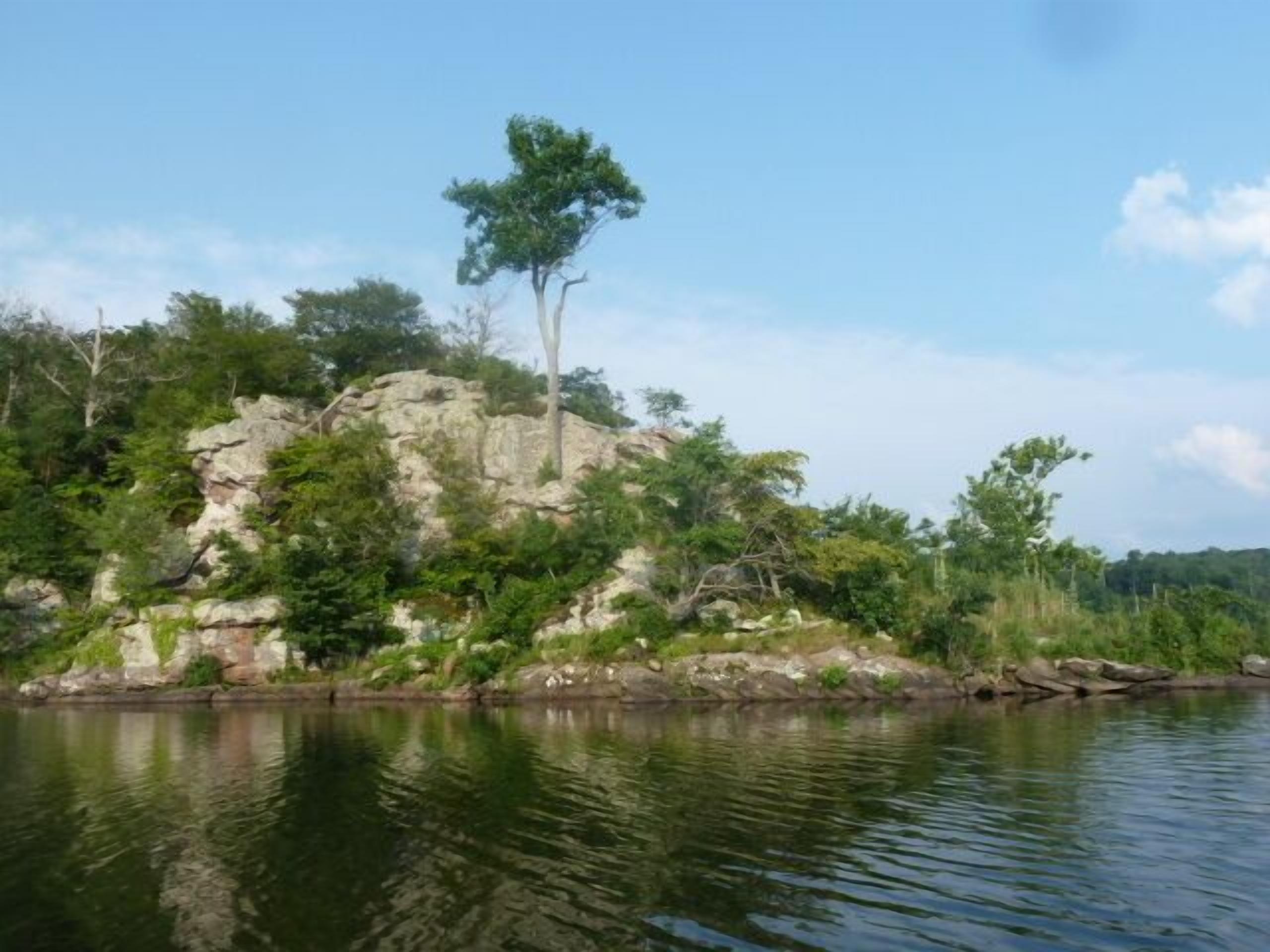 A rocky shoreline with a calm body of water reflecting the sky.