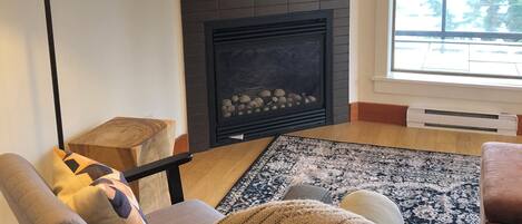 A living room with a fireplace, a television, a sofa, and a patterned rug.