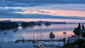 A marina with boats docked, a pier, and a backdrop of mountains and islands during twilight. - Two Bedroom Ocean View Condo, walk to Ganges -UNIT 203 (Salt Spring Island)
