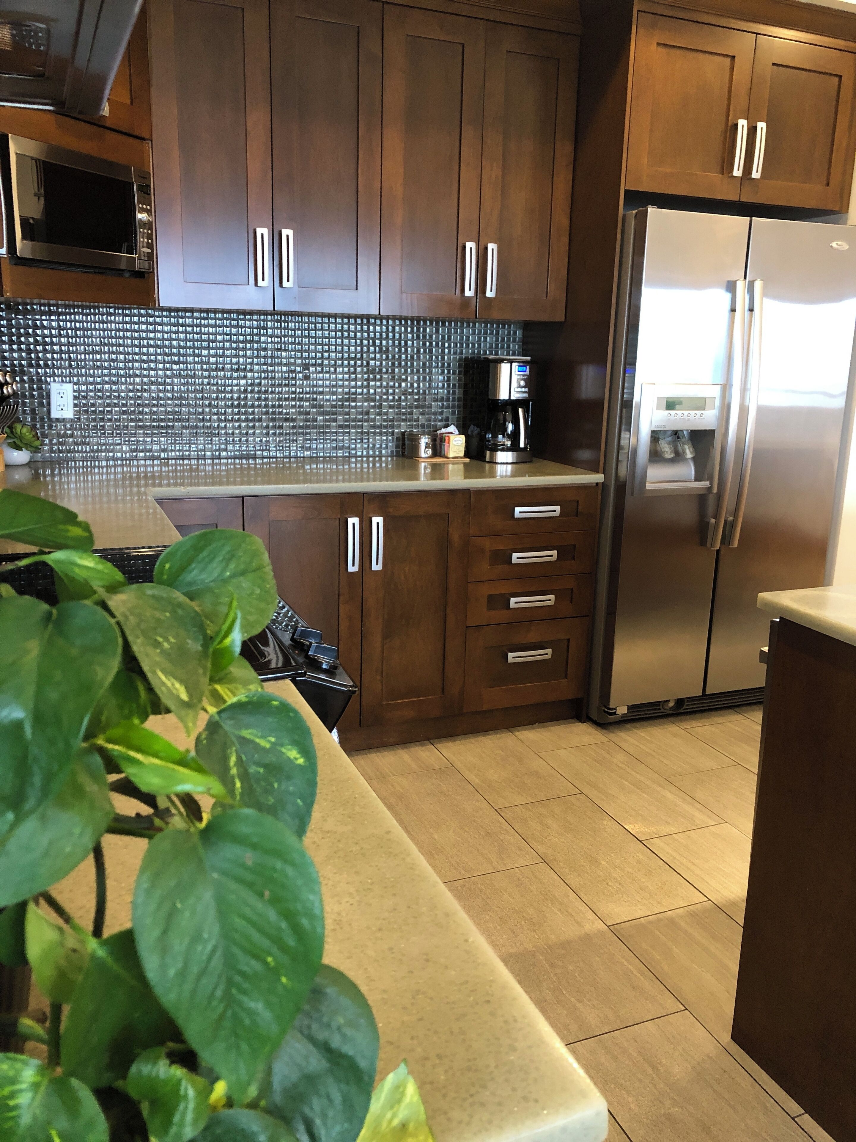 A modern kitchen with wooden cabinets, a stainless steel refrigerator, and a tiled backsplash.