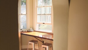 Eine Küche mit einem großen Fenster, zwei Barhocker und einer Arbeitsfläche.