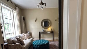 Ein Zimmer mit einer Couch, Hocker und einem kleinen Tisch mit Spiegel.