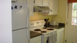 Une cuisine avec des meubles blancs, une cuisinière blanche et un grille-pain.