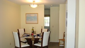 Une salle à manger avec une table ronde, quatre chaises et un tableau accroché au mur.