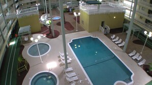 Una piscina interior con varias secciones, rodeada de sillones de descanso y piscinas más pequeñas.