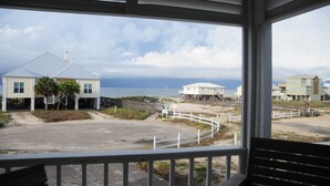 A beach house with a porch, a sandy area, and a view of the ocean. - Best First Tier House - Located in beautiful Morgantown (Gulf Shores)