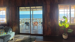 Un intérieur en bois avec une porte-fenêtre coulissante donnant sur un balcon avec vue sur la mer.