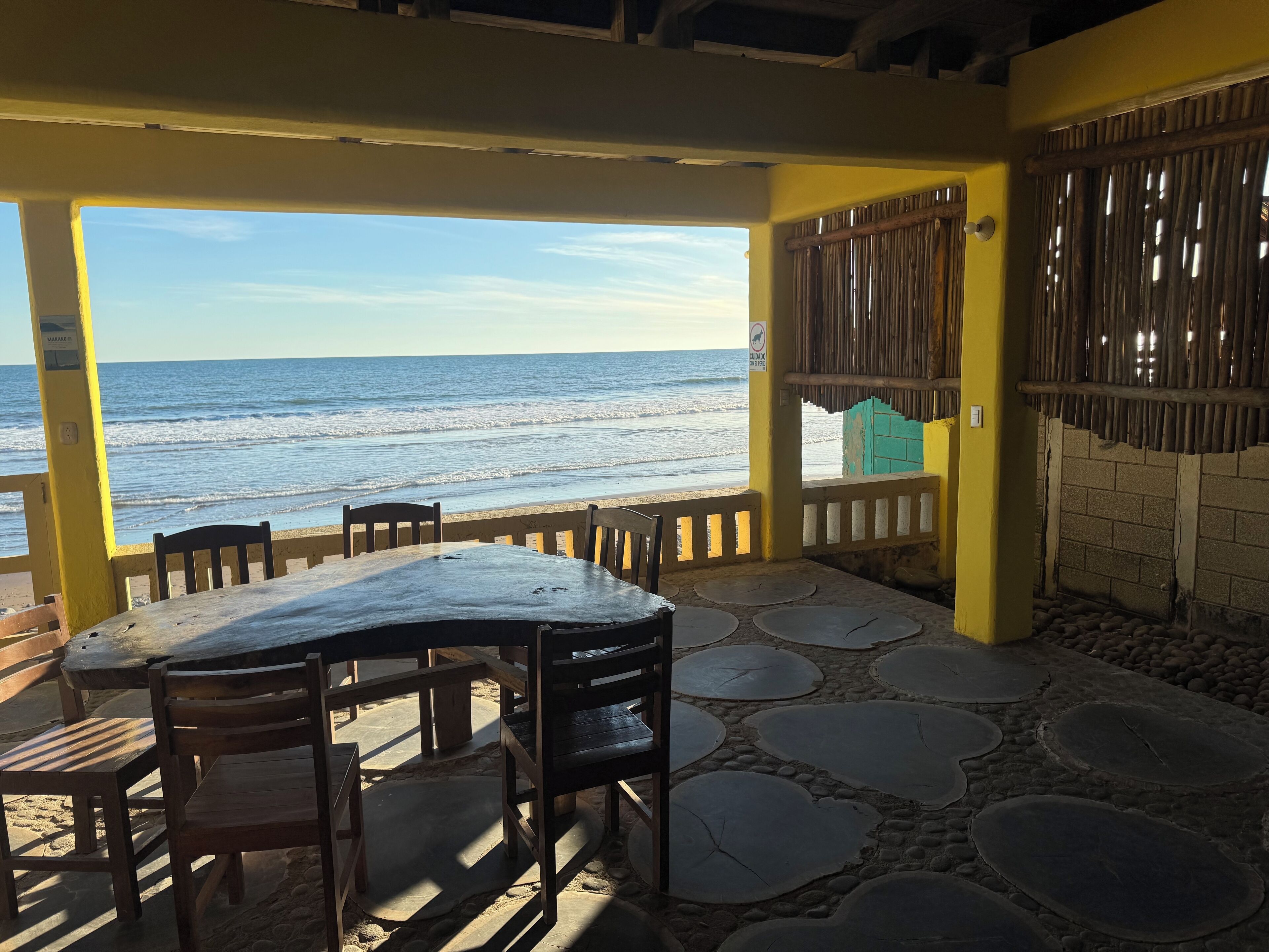 A covered outdoor seating area with a view of the beach and ocean.