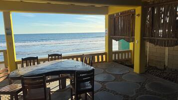 A covered outdoor seating area with a view of the beach and ocean.