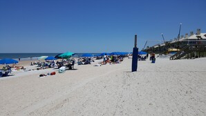 A beach with umbrellas, sun loungers, and a wooden walkway leading to a building. - SAWGRASS PONTE VEDRA BEACH (Ponte Vedra Beach)