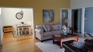 A living room with a grey sofa, a coffee table, and a dining area with a wooden table and chairs. - SAWGRASS PONTE VEDRA BEACH (Ponte Vedra Beach)