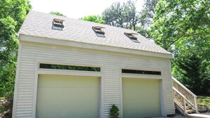 Een gelijkvloers gebouw met twee garagepoorten en een kleine trap naar een terras.