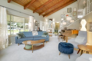 A spacious living room with a blue sofa, wooden coffee table, and a piano.