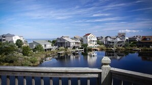 A waterfront property with houses along a calm body of water, a wooden deck, and a clear sky.