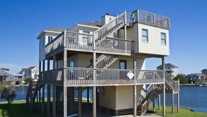 A multi-level waterfront property with a deck and stairs leading to the upper levels.
