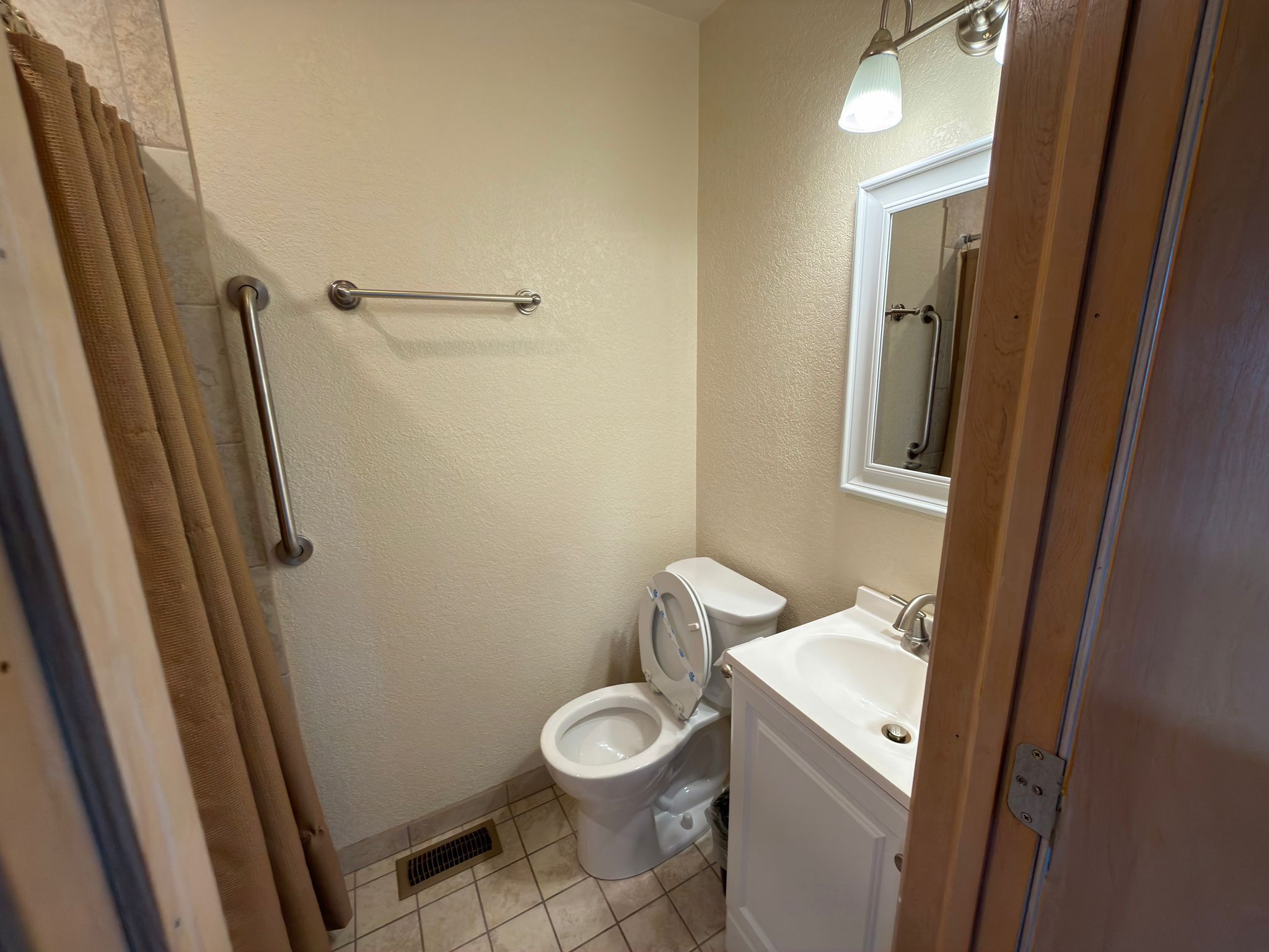 A small bathroom with a toilet, sink, and shower.