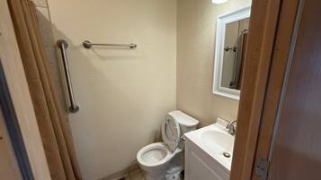 A small bathroom with a toilet, sink, and shower.