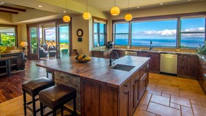 A spacious kitchen with a large island, wooden cabinets, and a view of the ocean. - Kula Luxury Retreat With Stunning Ocean & Mountain Views! (Kula)