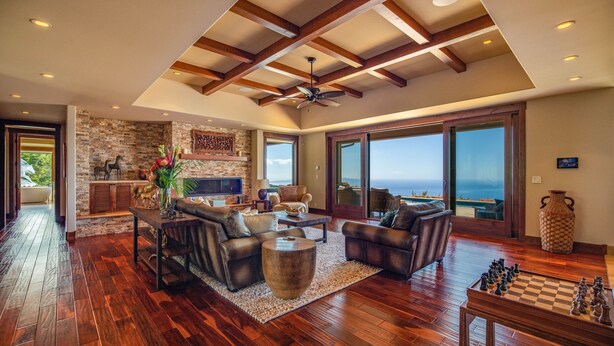 A spacious living room with a fireplace, leather sofas, a coffee table, and a chessboard. - Kula Luxury Retreat With Stunning Ocean & Mountain Views! (Kula)