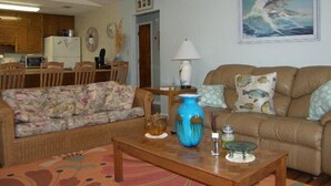 A living room with a sofa, a coffee table, and a dining area with chairs and a table. - Southern Tide in Indian Pass 😊 (Indian Pass)