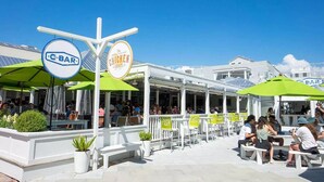 An outdoor seating area with white tables and green umbrellas, a sign for 'C Bar' and 'Chicken Shack', and a clear blue sky. - 5 BR, 5 BA in Seaside, quick walk to the private beach access or main pool  (Santa Rosa Beach)