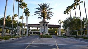 A gated entrance with palm trees, a covered walkway, and a clear sky. - TOP REVIEWED HOME! Only 3 MILES to Disney, South Pool in Emerald Island Resort (Kissimmee)