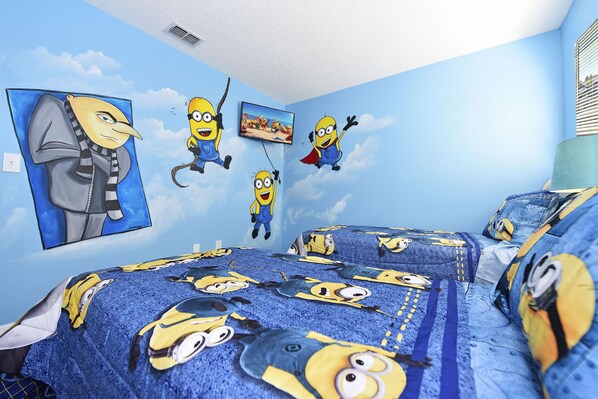 A room with a Minion-themed bedspread, wall art, and a painting of a character.