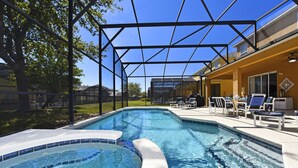 A swimming pool with a curved edge, surrounded by a covered patio area with lounge chairs and a barbecue grill. - TOP REVIEWED HOME! Only 3 MILES to Disney, South Pool in Emerald Island Resort (Kissimmee)